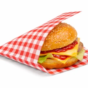 Red gingham open-sided takeaway bag holding a cheeseburger, with a matching sheet underneath